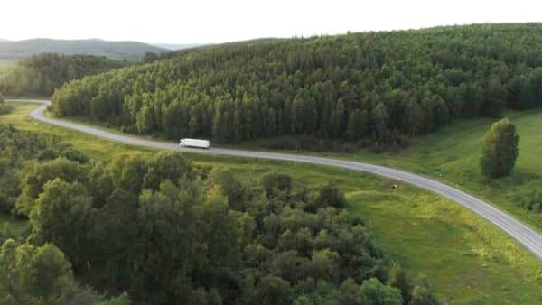 Panorama with truck driving on highway in summer. Action. Beautiful summer landscape with green
